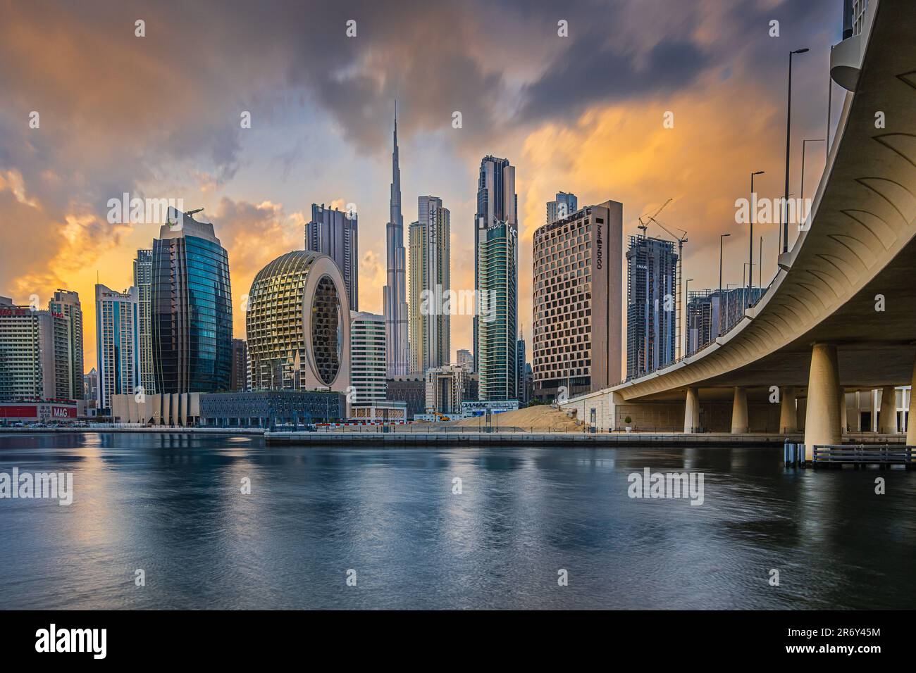 Evening mood in Dubai. Sunset with the city skyline in Emirates. Cloudy skies with skyscrapers overlooking Burj Khalifa. Glazed facade of skyscrapers. Stock Photo