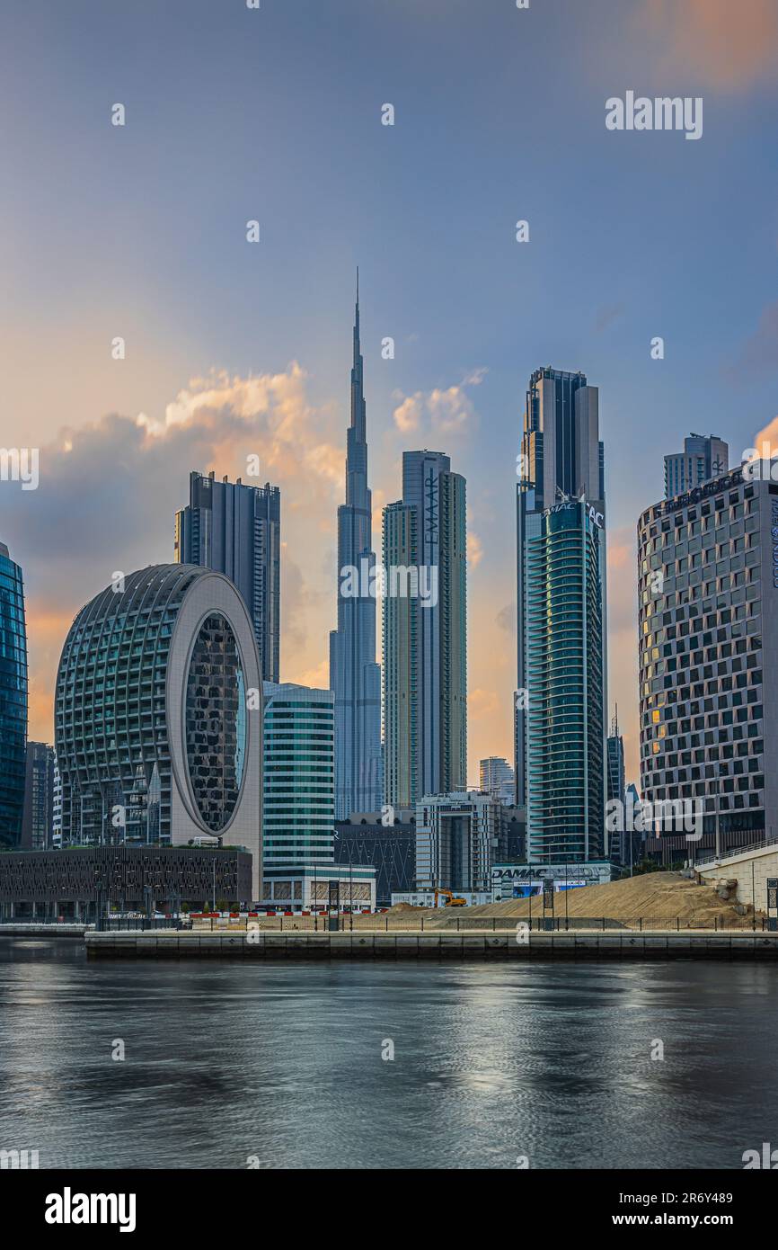 View of the skyscrapers with Burj Khalifa of Dubai. Arabic city skyline in the evening. Evening mood with a cloudy sky at sunset. Port and canal Stock Photo