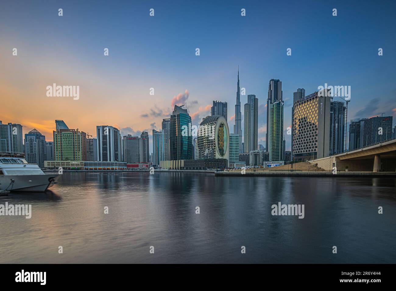 Skyline with skyscrapers of Dubai in the United Arab Emirates. City center with business and office buildings in the evening at sunset. Port with boat Stock Photo