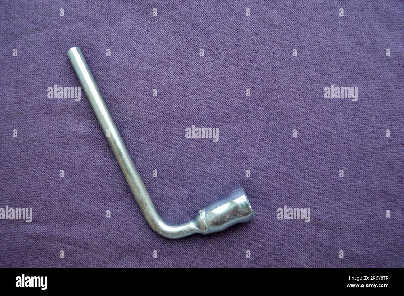 Silver, metal end wrench on a background of purple fabric. Bench tools. Stock Photo
