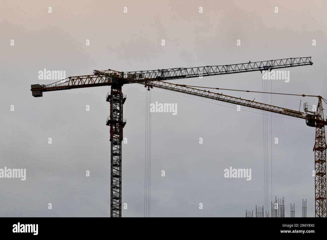 Large powerful construction cargo industrial crane on a construction site of new buildings and houses against the sky. Stock Photo
