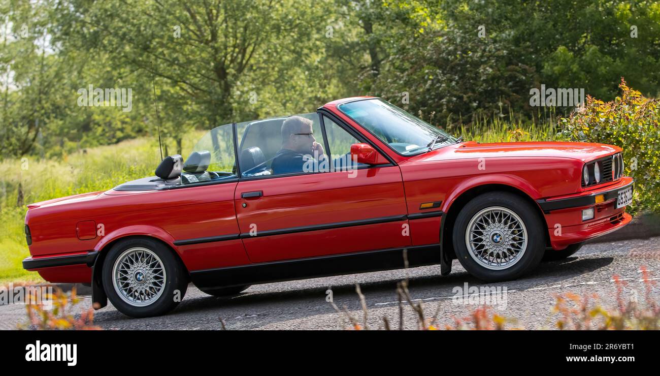 Stony Stratford,UK - June 4th 2023:  1990 red BMW 3 SERIES 325I CABRIOLET classic car travelling on an English country road. Stock Photo