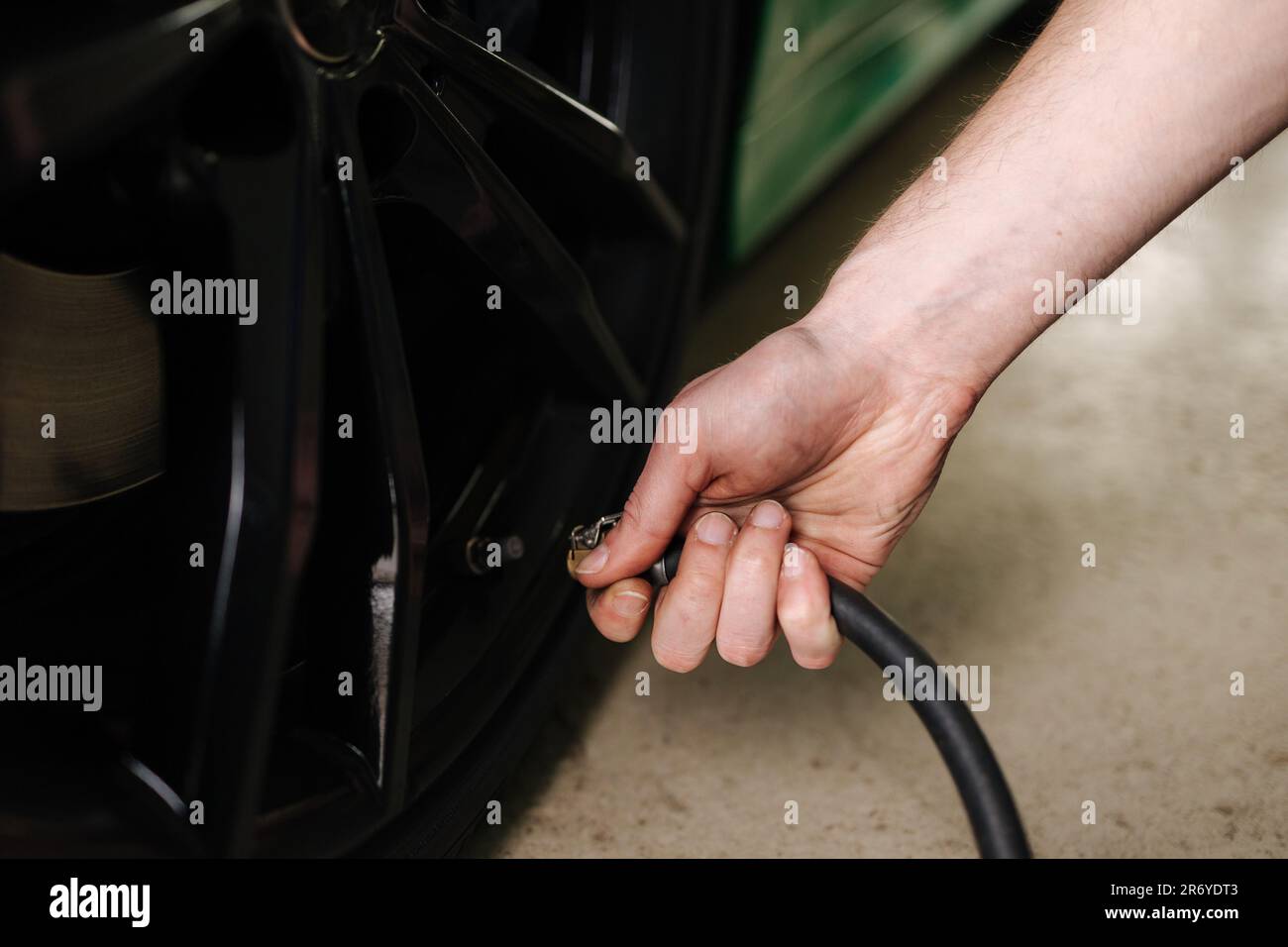 Man inflates the tires on auto service. Mechanic in glasses inspection the car at garage Stock