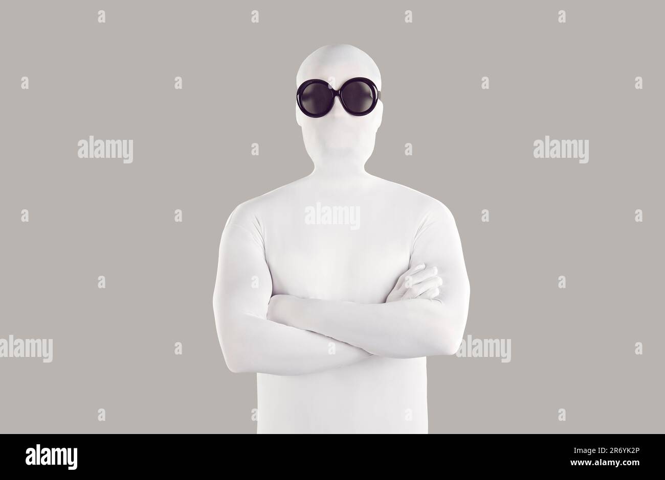 Portrait of person in white bodysuit costume and black sunglasses with folded arms Stock Photo