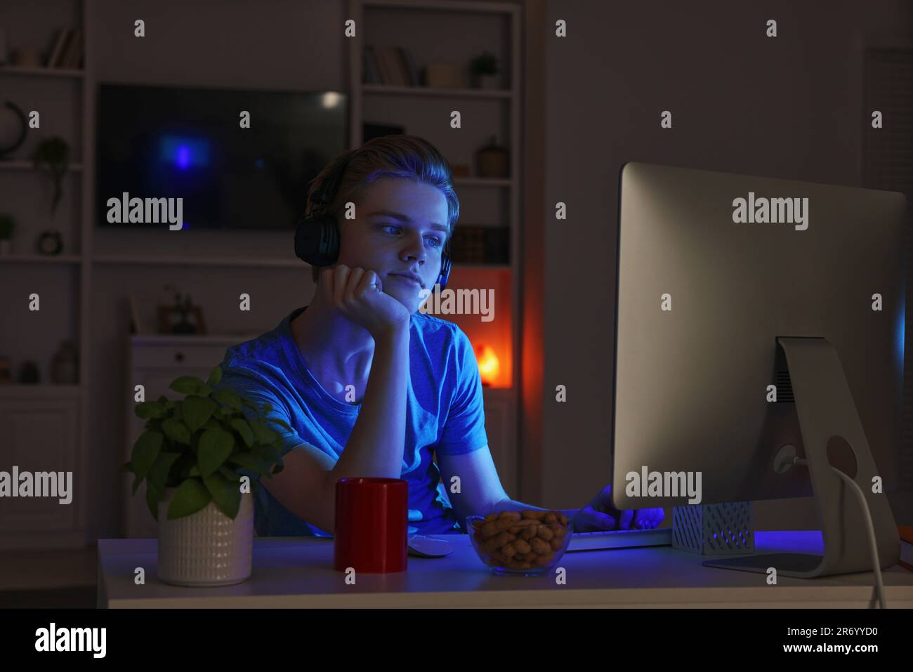 Teenage boy using computer in bedroom at night. addiction