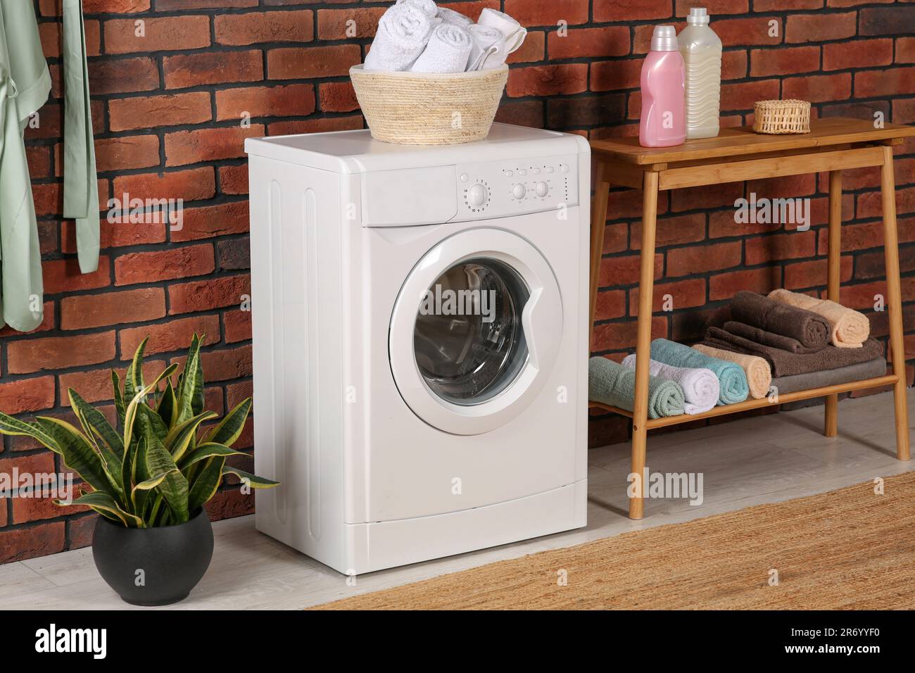 View of Washing machine and wooden console table with terry towels indoors ...
