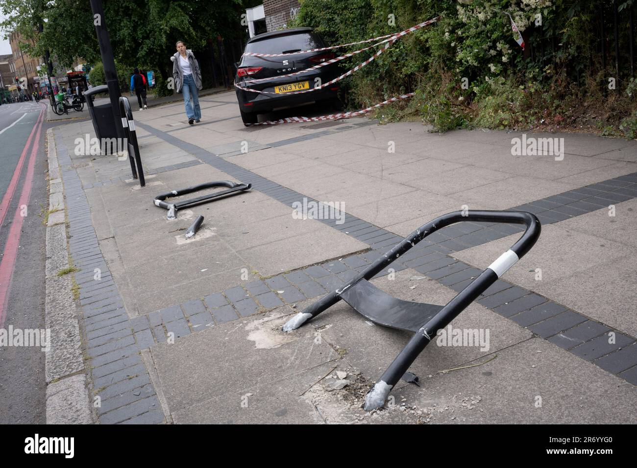 Police tape surrounds a wrecked hatchback car that mounted the pavement