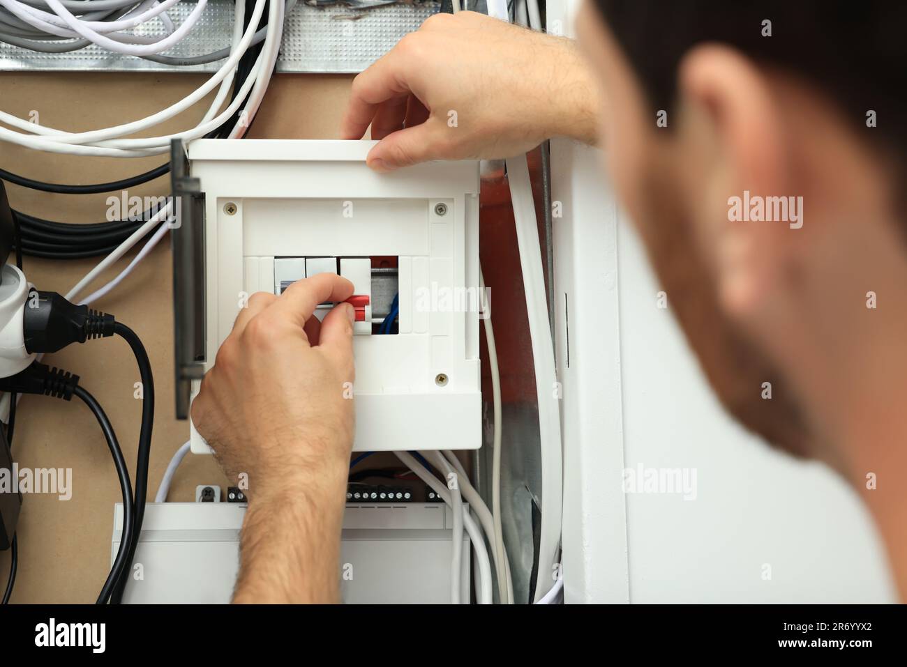 Electrician switching off circuit breakers in fuse box, closeup Stock Photo