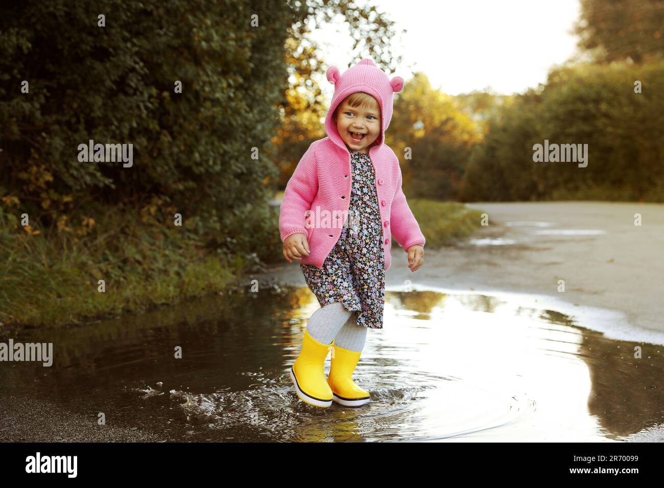 Little girl wearing rubber boots walking in puddle outdoors Stock Photo ...