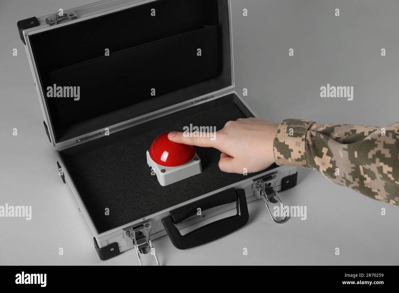 Serviceman pressing red button of nuclear weapon on light gray ...