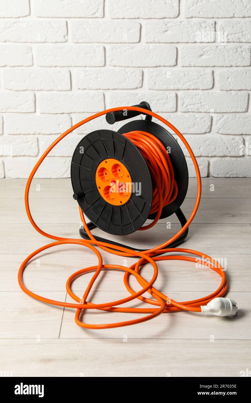 Extension cord reel on floor near white brick wall. Electrician's ...