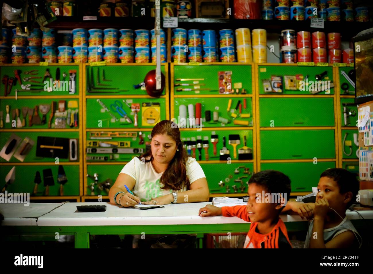 A woman works in a brightly colored hardware store in a slum in Caracas ...