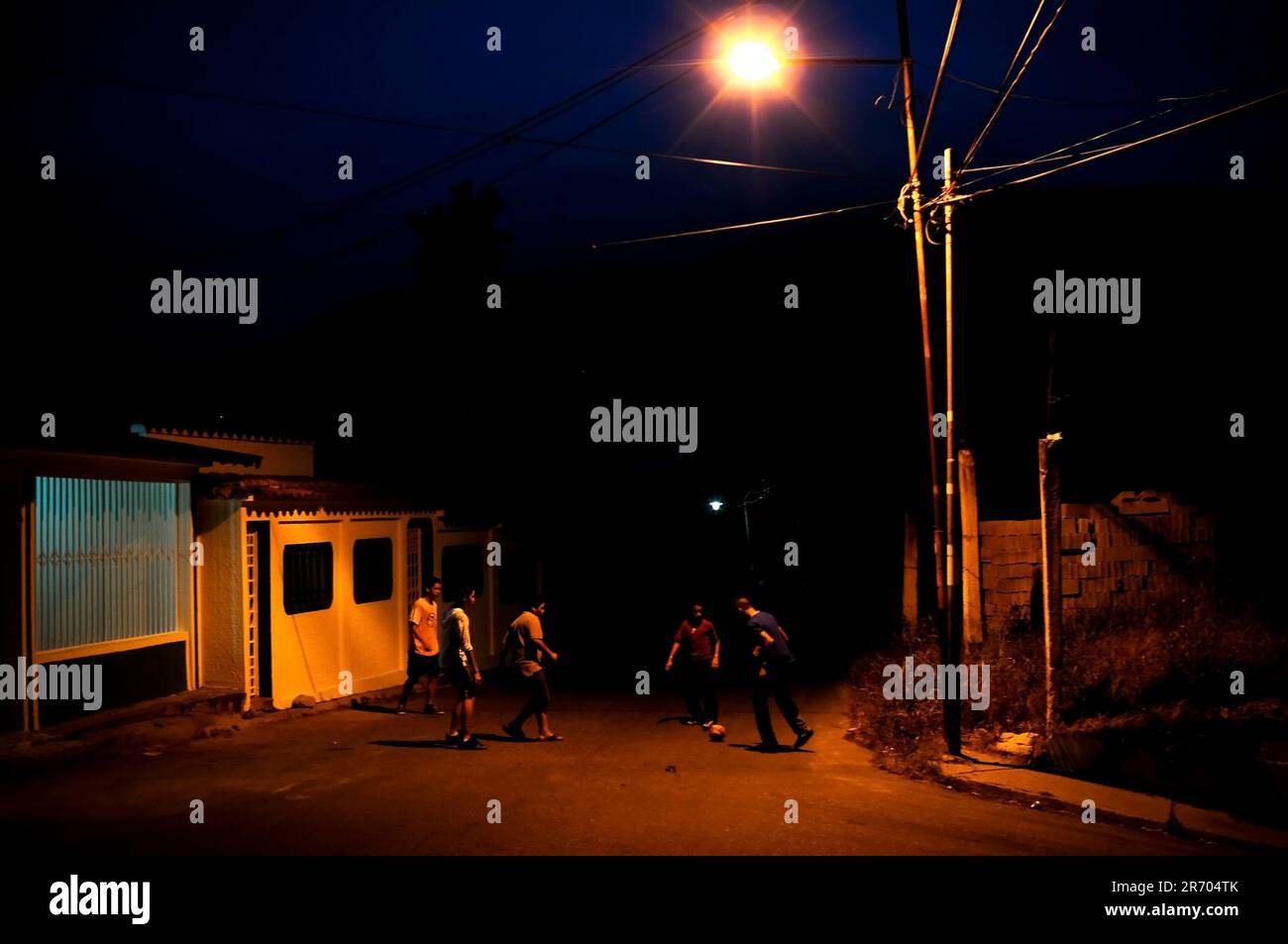 Young men play soccer in the street at night in Tovar, Venezuela. Stock Photo