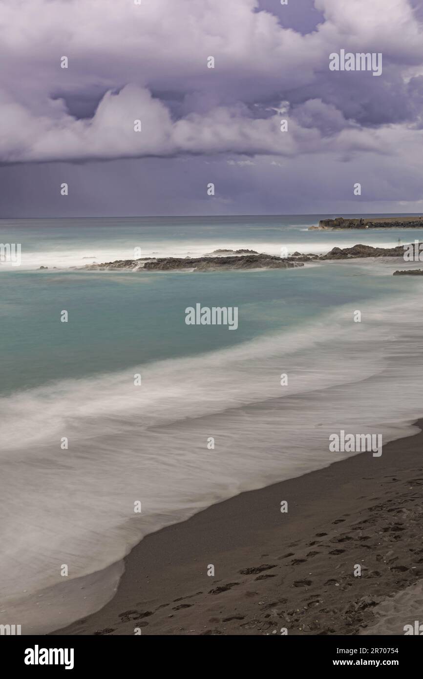 Very dark rain clouds over the Atlantic ocean, Playa Jardin beach, long exposure,  Puerto de la Cruz, Tenerife, Canary islands Stock Photo