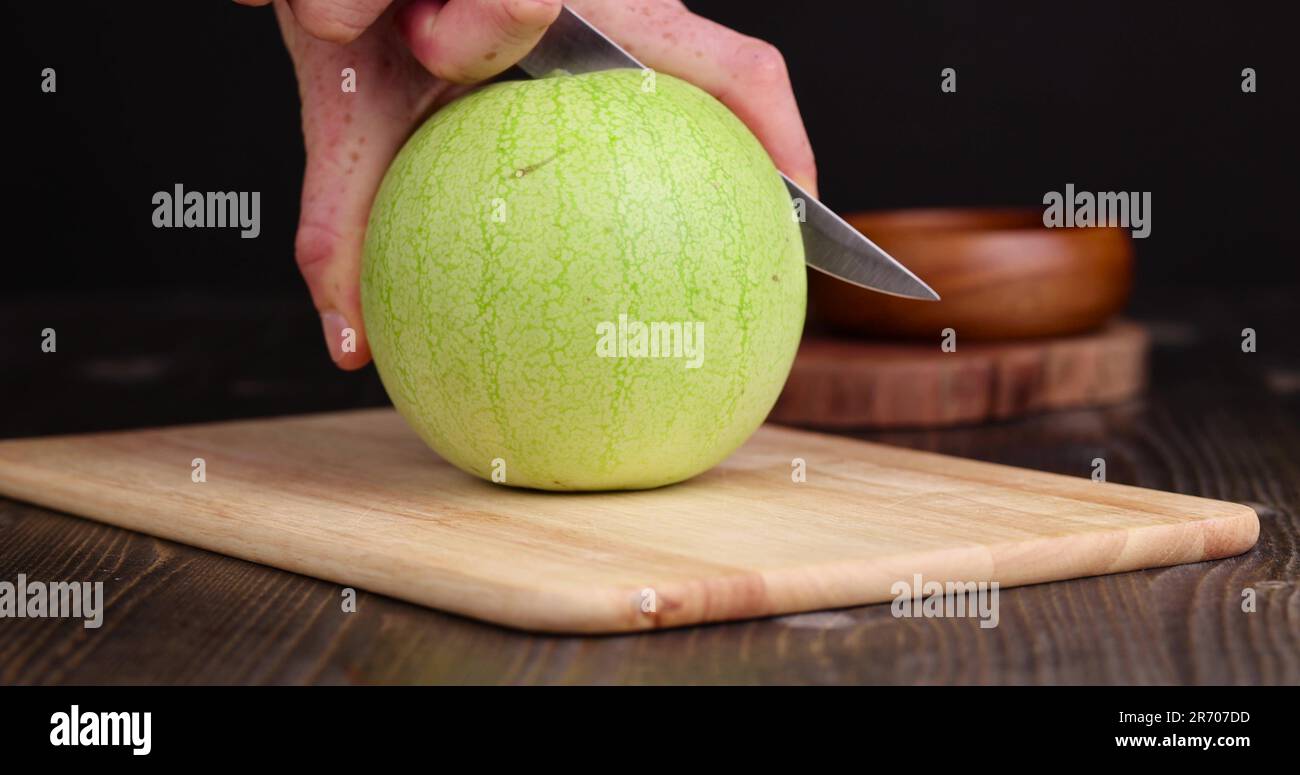 Cut an unripe small watermelon on the table, cut a red and white unripe ...