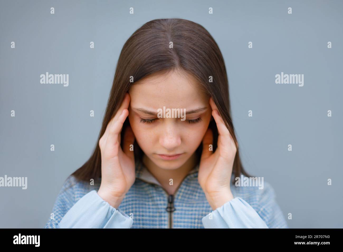 teen girl suffering of headache on blue gray background. Troubled