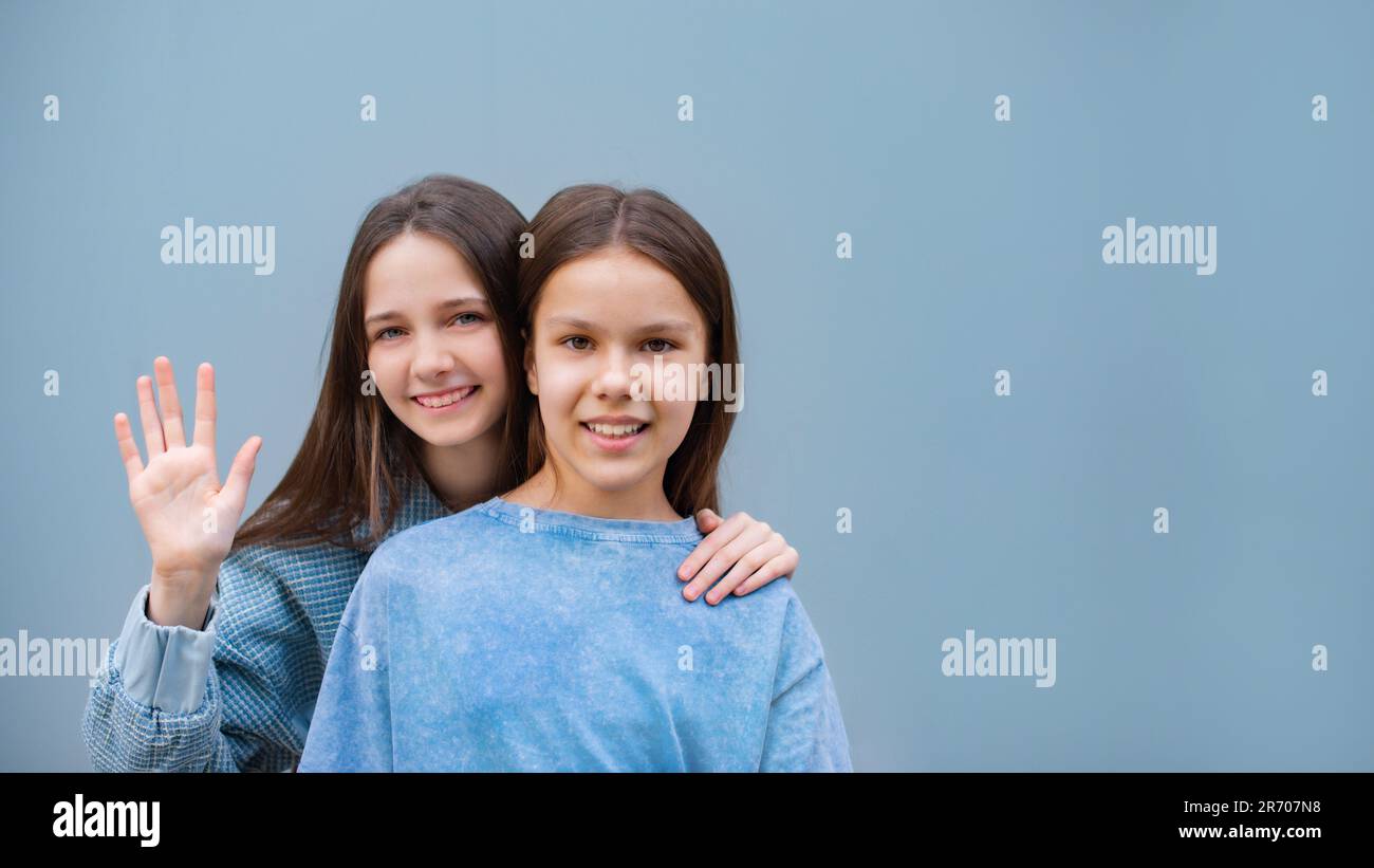 two cheerful teen girls hand on shoulder toothy smile look camera isolated on blue color background Stock Photo