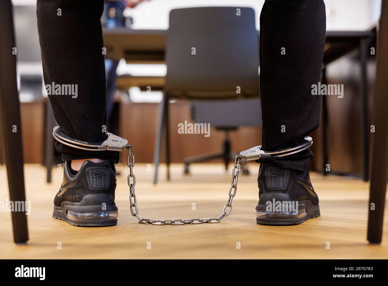 Nuremberg, Germany. 12th June, 2023. A man accused of computer fraud worth millions of euros sits in the courtroom at the Nuremberg-Fürth Regional Court with his feet shackled as the trial begins. A total of six defendants, five men and one woman, are alleged to have used fake text messages to trick more than 360 people into handing over their online banking access data between April 2021 and March 2022. In the process, they are said to have looted around 1.4 million euros. The charges include gang and commercial computer fraud and forgery. Credit: Daniel Karmann/dpa/Alamy Live News Stock Photo
