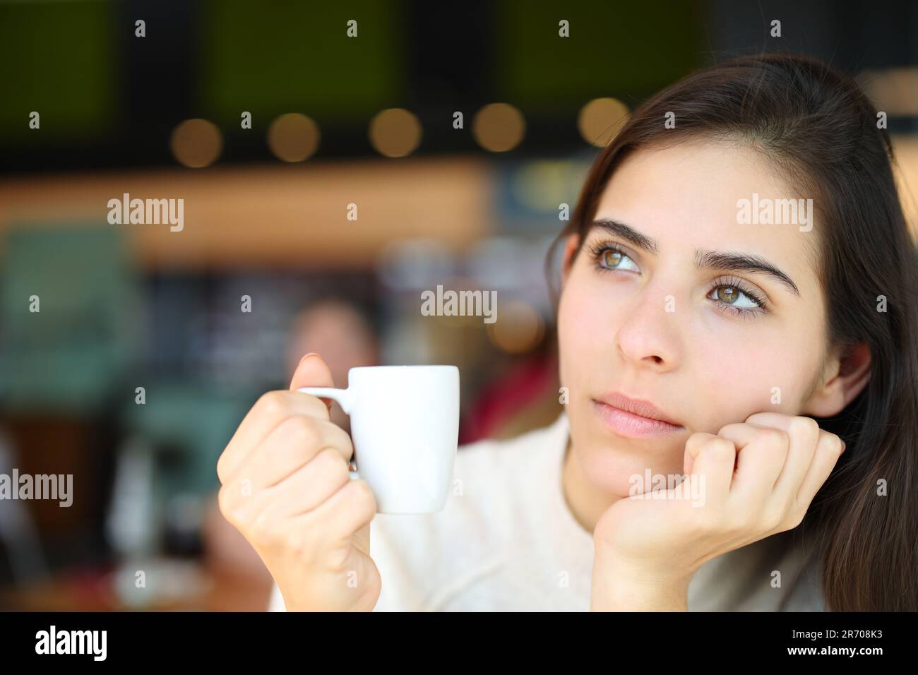 Pensive serious woman holding coffee cup in a bar interior Stock Photo
