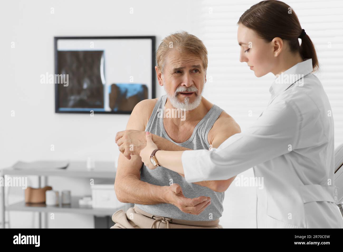 Orthopedist Examining Patient With Injured Arm In Clinic Stock Photo 