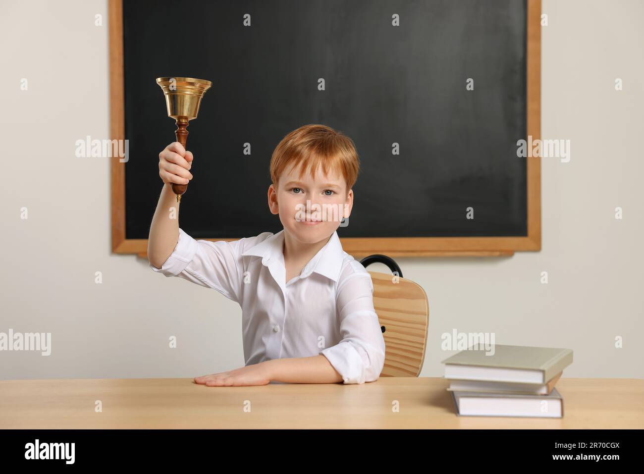 Cute little boy ringing school bell in classroom Stock Photo Alamy