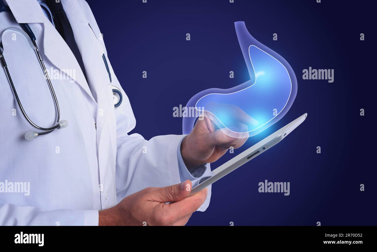 Symptoms and treatment of heartburn and other gastrointestinal diseases. Doctor using tablet on blue background, closeup. Stomach illustration over de Stock Photo