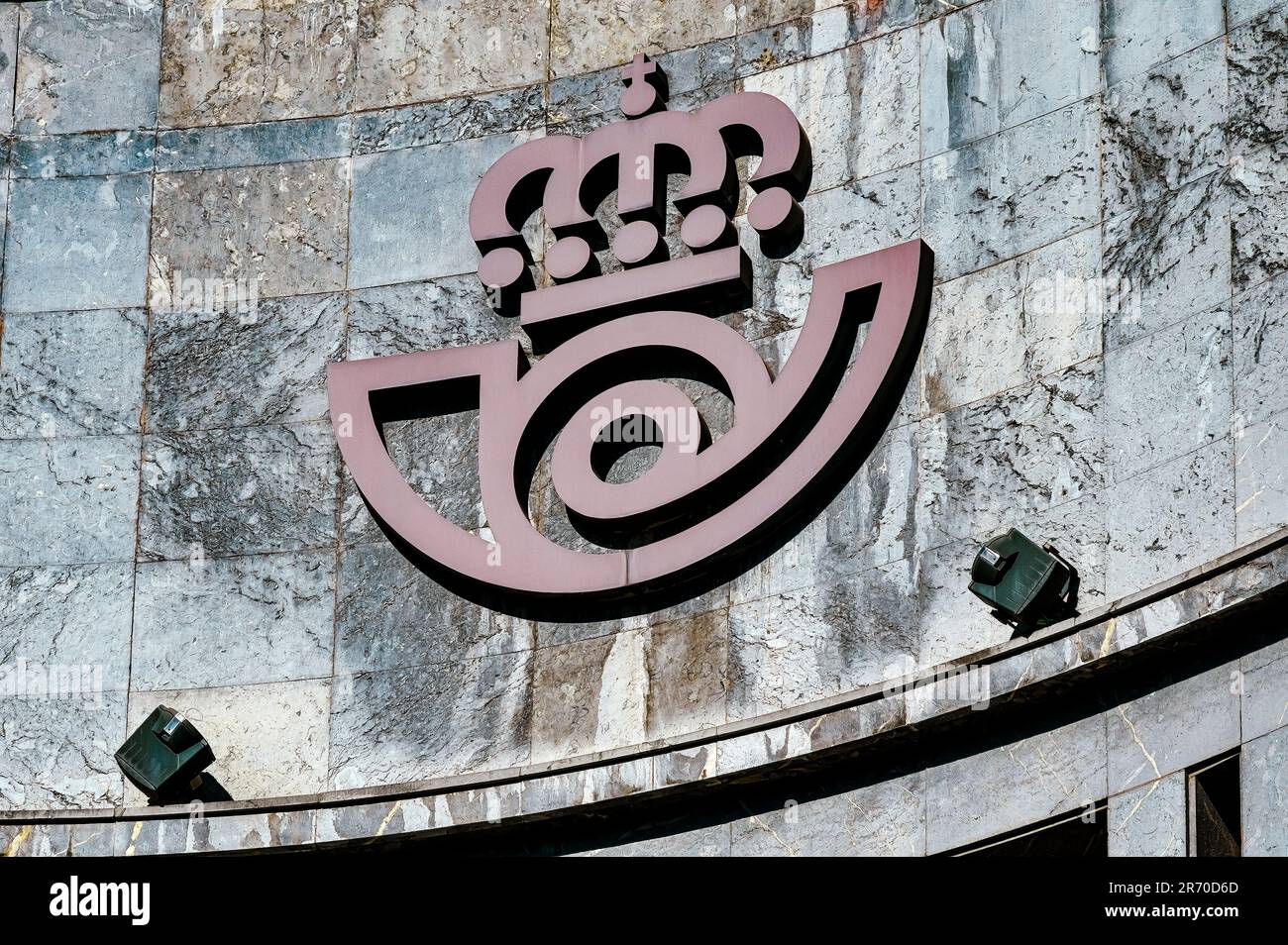 Oviedo, Asturias, Spain: A weathered building wall with an embossed logo.  The sign is illuminated by two electric lamps. Stock Photo