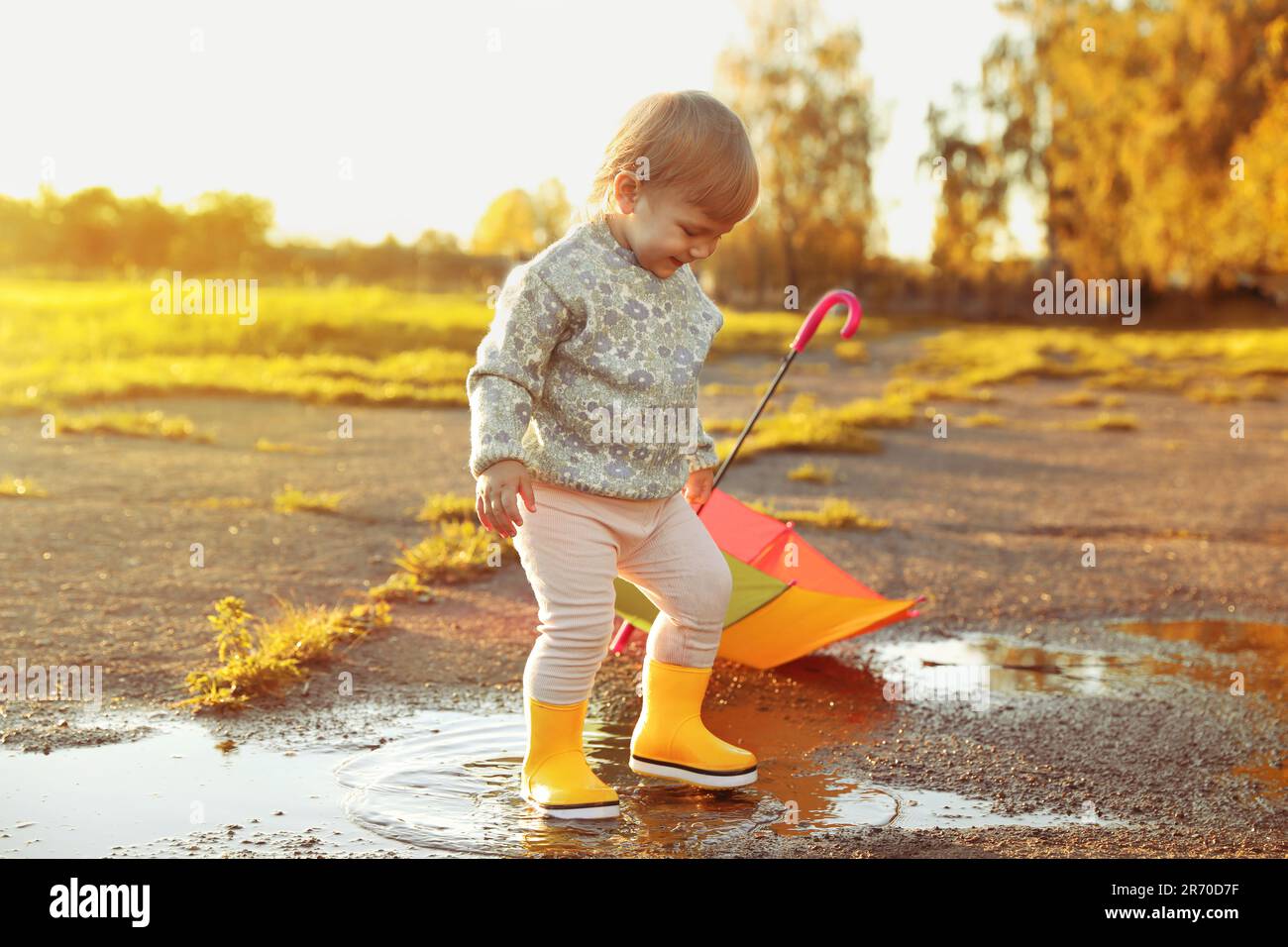 Little girl wearing rubber boots walking in puddle outdoors Stock Photo ...