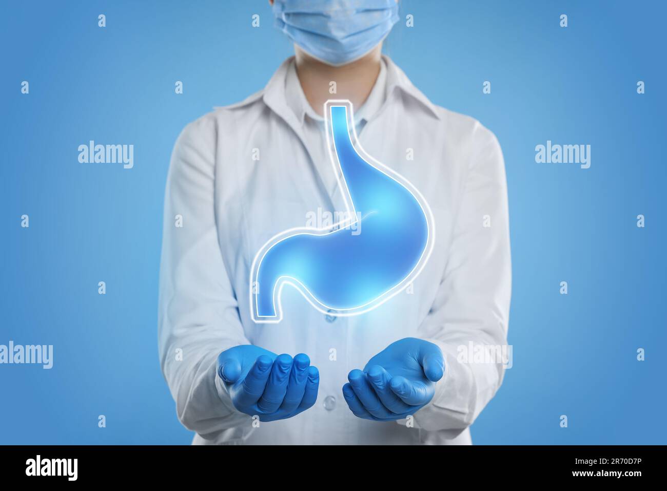 Symptoms and treatment of heartburn and other gastrointestinal diseases. Doctor holding stomach illustration on light blue background, closeup Stock Photo