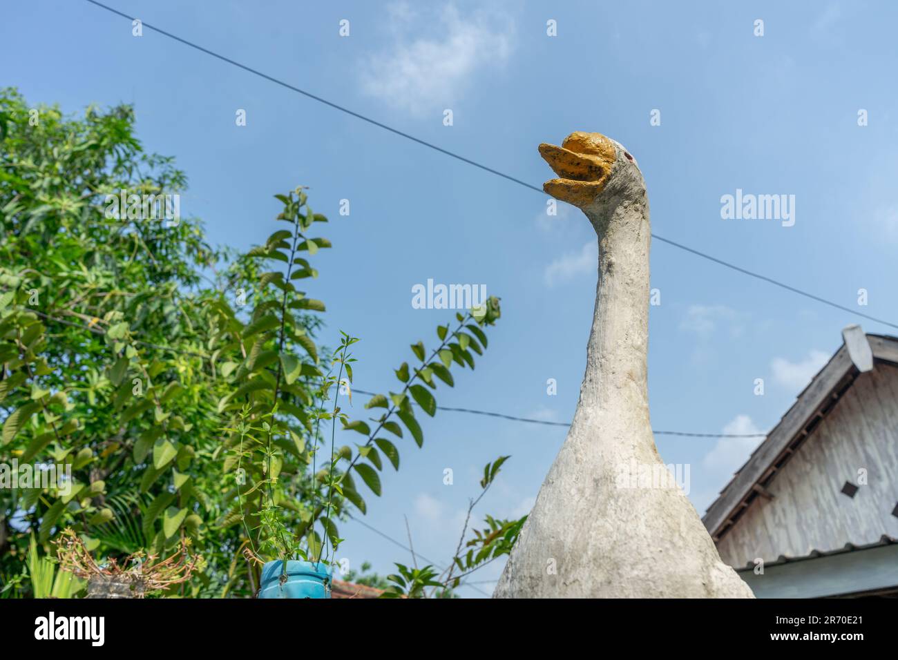 A white swan statue under a skyblue is seen from below. Swan statue made of  cement Stock Photo - Alamy