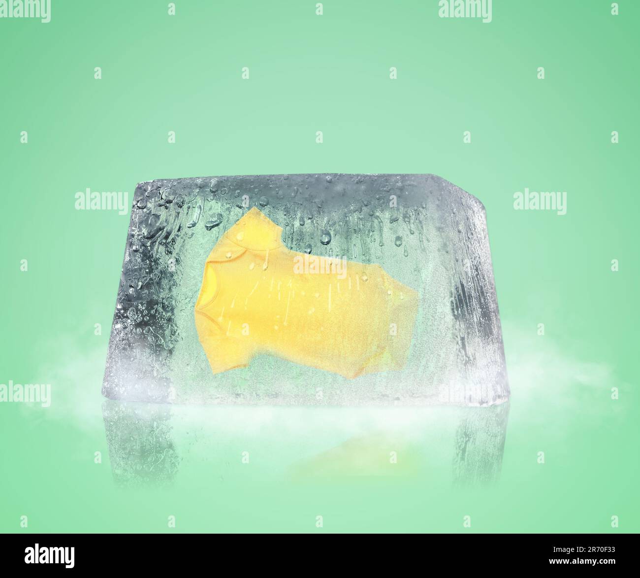 Conservation of genetic material. Baby onesie in ice cube as cryopreservation on light green background Stock Photo