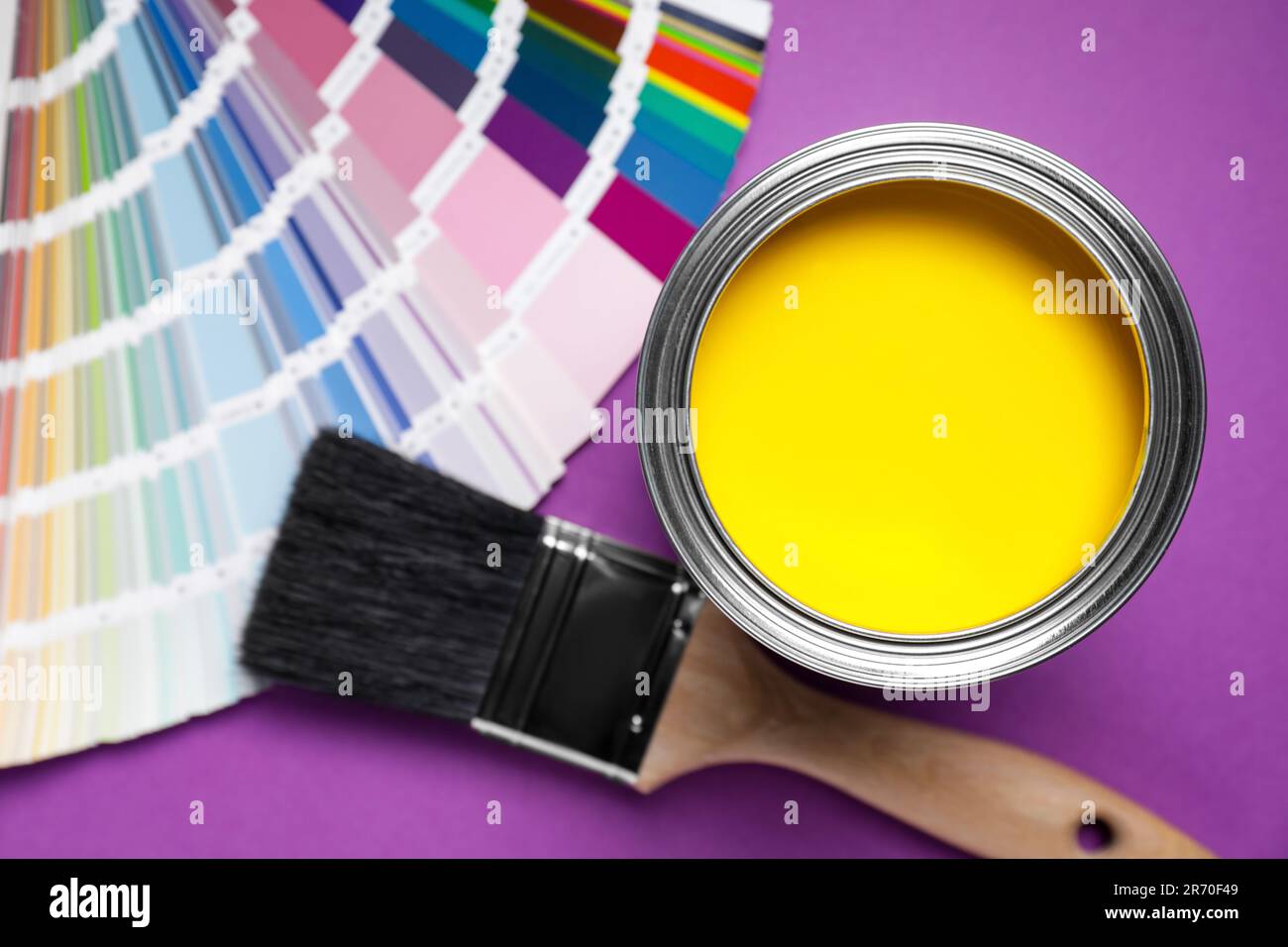 Can with yellow paint, color palette and brush on purple background, flat lay Stock Photo