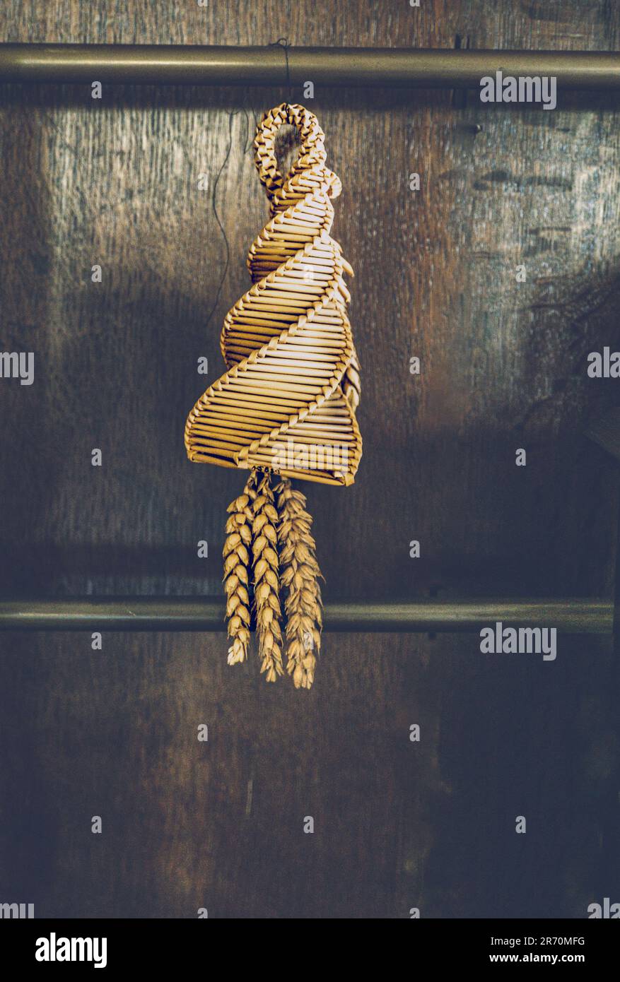 A traditional English harvest 'Corn Dolly' ( Earth Mother ) hanging up from oak panelling in an English manor house. Stock Photo