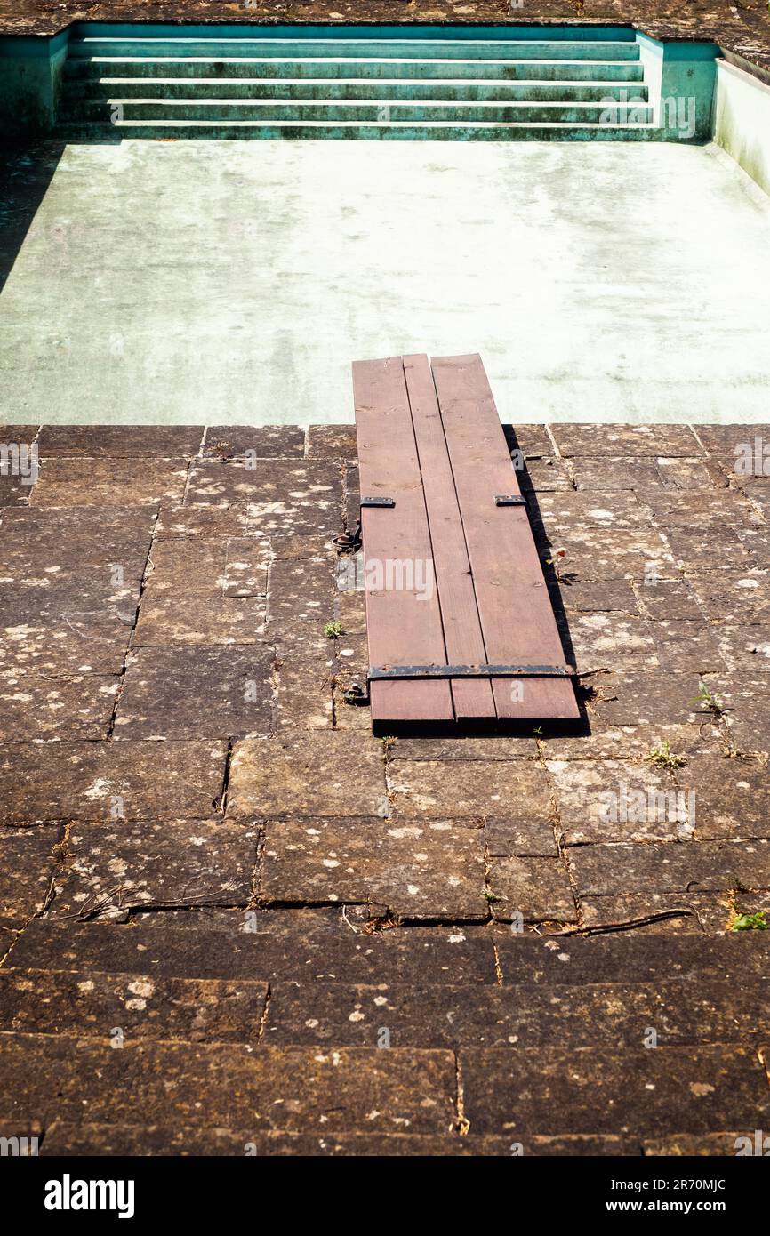 A diving board and a drained swimming pool and old fashioned wooden