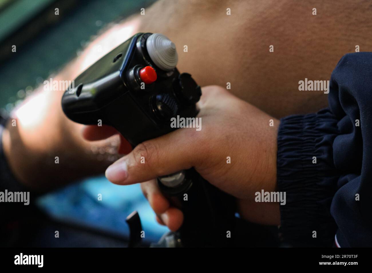 A young man holding a red-buttoned game controller in his hands Stock Photo