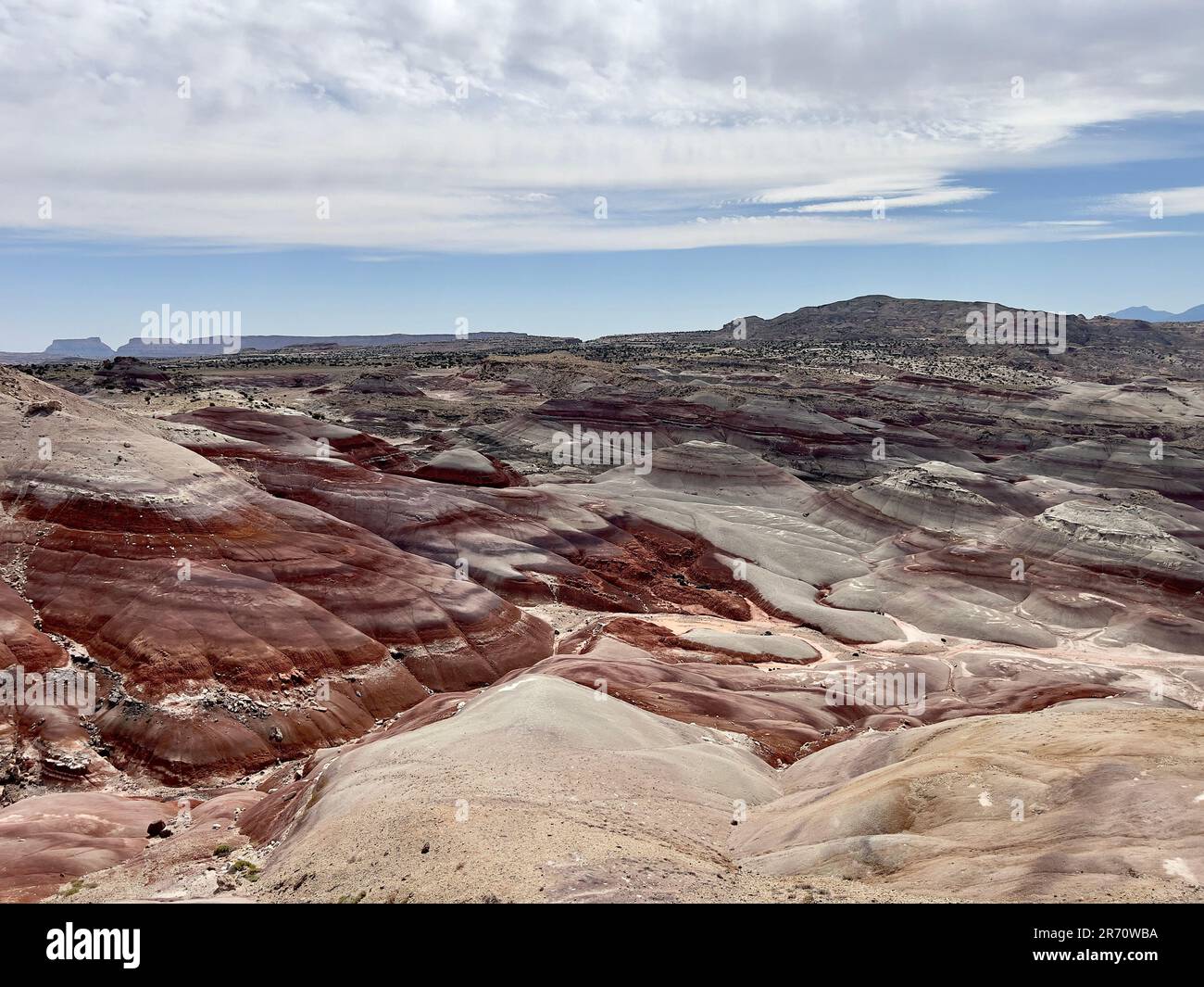 A scenic desert landscape with hills and a bright blue sky with white ...