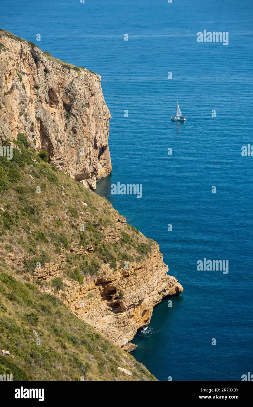 Sailboat sailing by Cova dels Òrguens coast in Spain Stock Photo