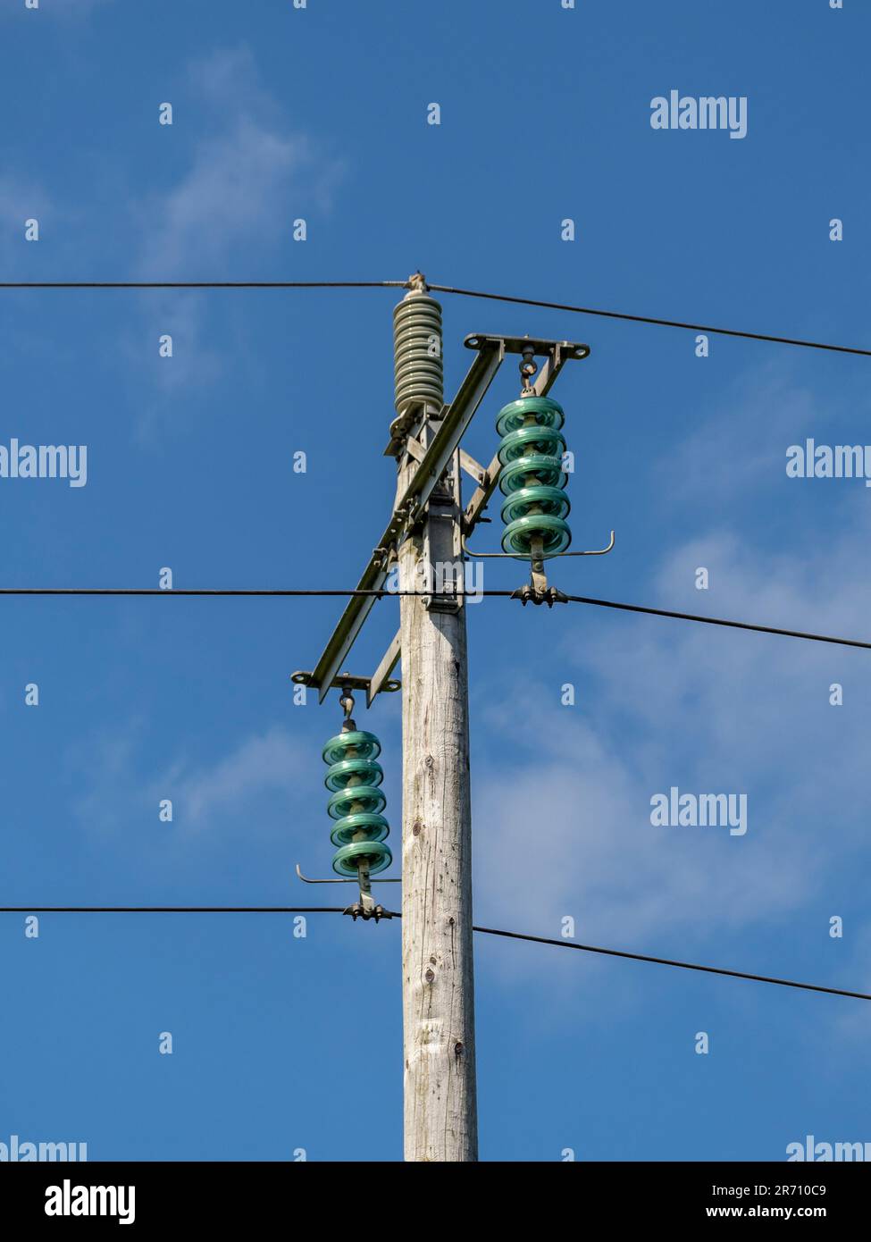 Wooden electricity poles with glass insulators between the cables. UK
