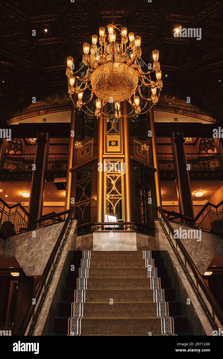 An ornate crystal chandelier hangs in the grand stairwell of a luxury cruise liner, adding a touch of sophistication to the regal atmosphere Stock Photo