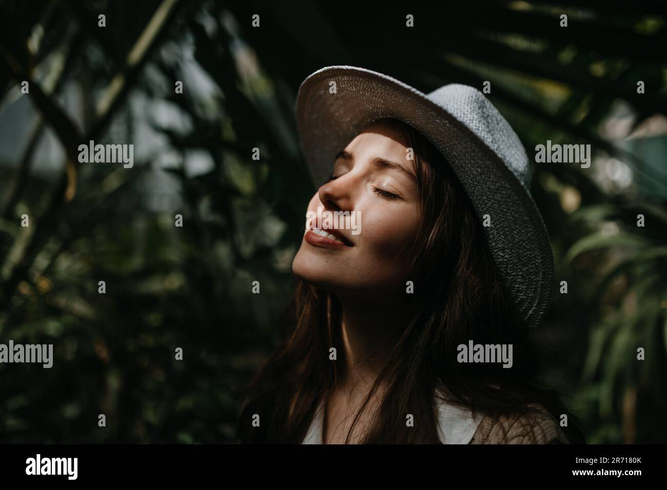 Portrait of young woman with hat in botanical garden. Stock Photo