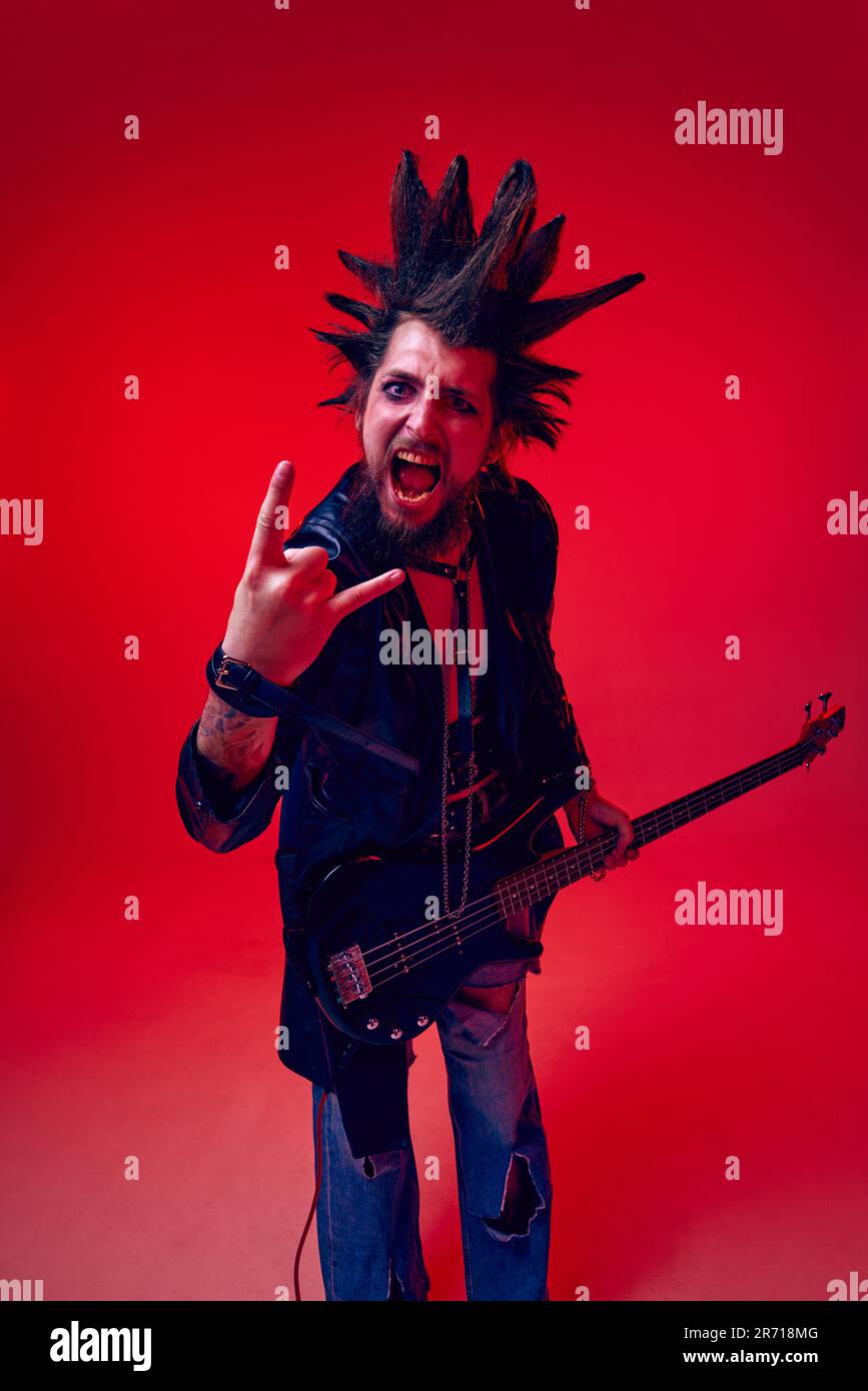 Punk rock man with red electric guitar and mohawk haircut. Expressive face.  Isolated on black background. Studio shot. Stock Photo by ©ysbrand 13166087