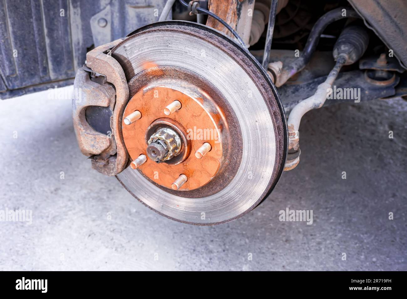 An old rusty car brake disc is lubricated with copper grease before
