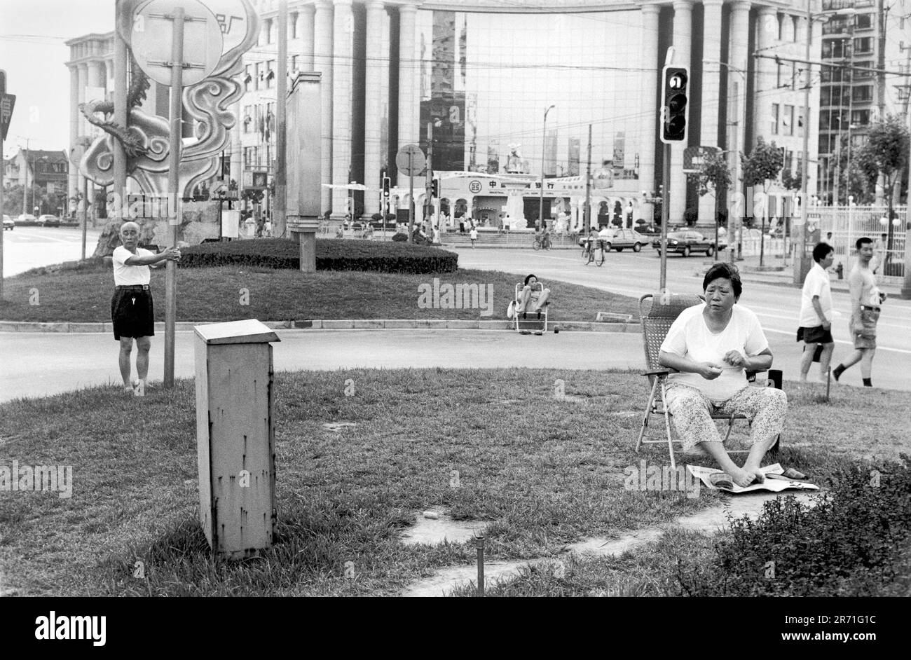 Shanghai China 2000.  In summer the heat and humidity in Shanghai can be stifling. During the evening residents enjoy the green open space of the central reservation in Fuxing Dong Lu.  This area is at the junction of the old Chinese city and the French Concession.  The latter was famous for its plane trees that used to provide welcome shade in summer until they were swept away to widen the roads. 2000s HOMER SYKES Stock Photo