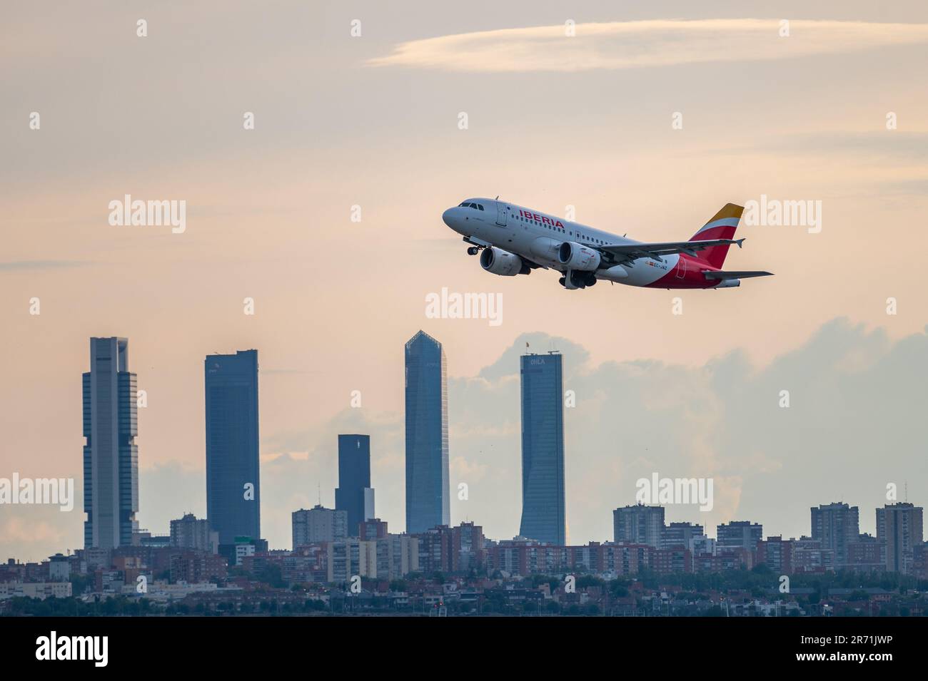 An Airbus A319 of Iberia comercial flight flies over the skyscrapers of Madrid's skyline, known as the 'Four Towers Business Area', after departing fr Stock Photo