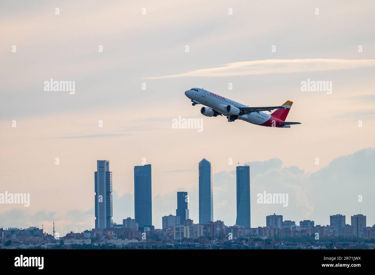 An Airbus A320 of Iberia comercial flight flies over the skyscrapers of Madrid's skyline, known as the 'Four Towers Business Area', after departing fr Stock Photo
