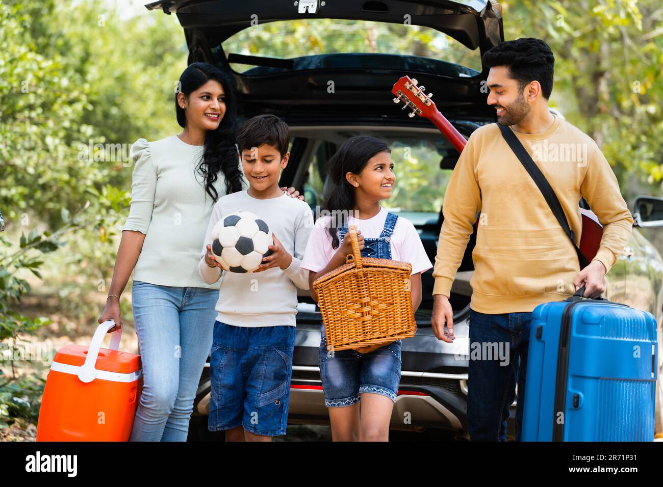 Happy indian fmaily with kids with picnic basket and travel lagguage at