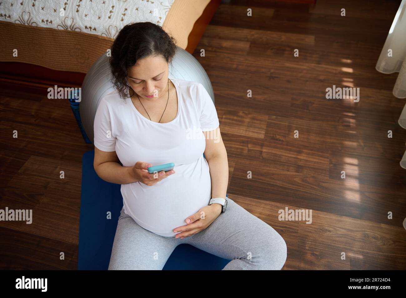 Pregnant woman checking pregnancy mobile app on her smartphone