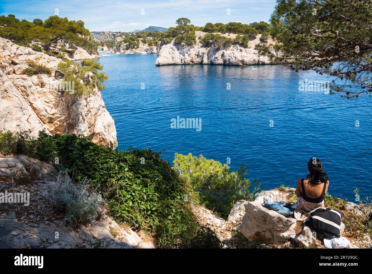 Young woman (unidentified; back view) admiring beautiful view of Calanque de Port-Miou with sailing boats mooring in its marina. France. Stock Photo