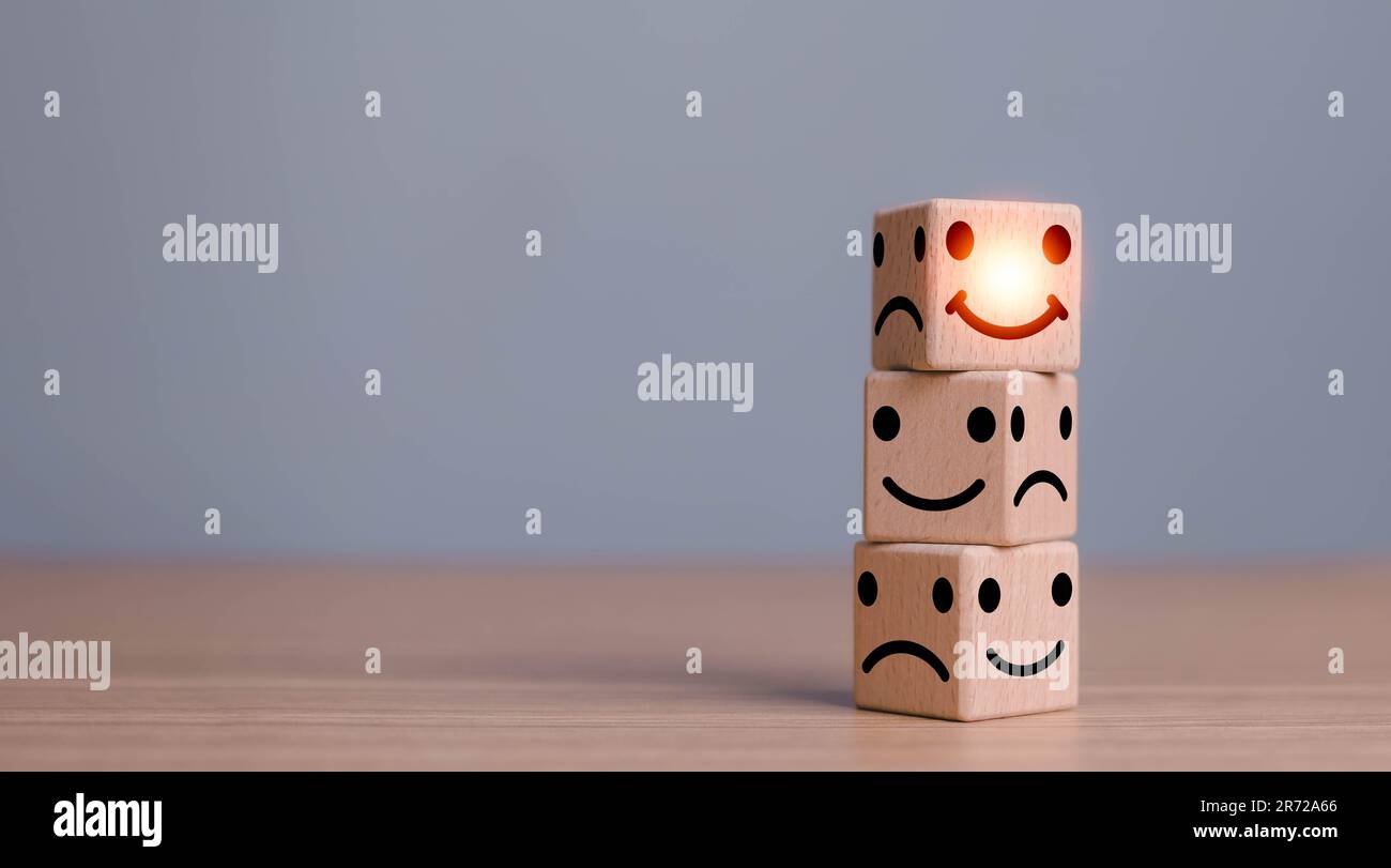 Smile face in bright side and sad face in dark side on wooden block