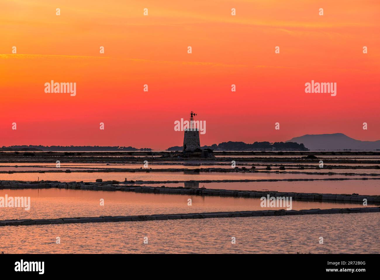 Sunset at the salt flats with the old windmill, saline dello Stagnone. Marsala, Trapani, Sicily, Italy, Europe. Stock Photo